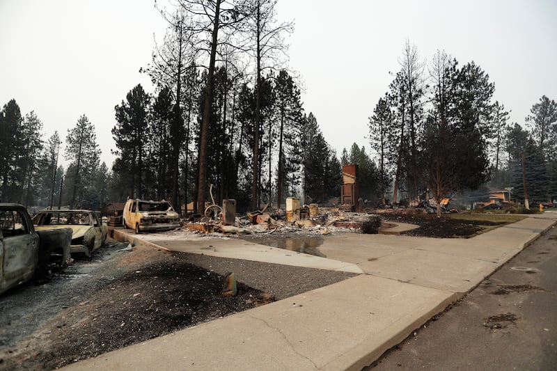 Los escombros se dispersan alrededor de estructuras quemadas después de un incendio forestal, domingo, 2 de agosto de 2026, en Spokane, Washington.