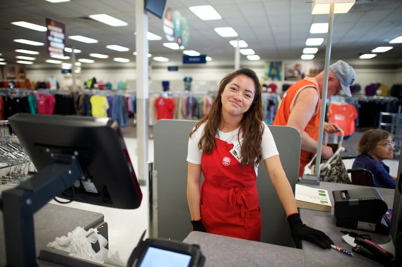 Una asociada de Deseret Industries sonríe mientras trabaja en la caja registradora.