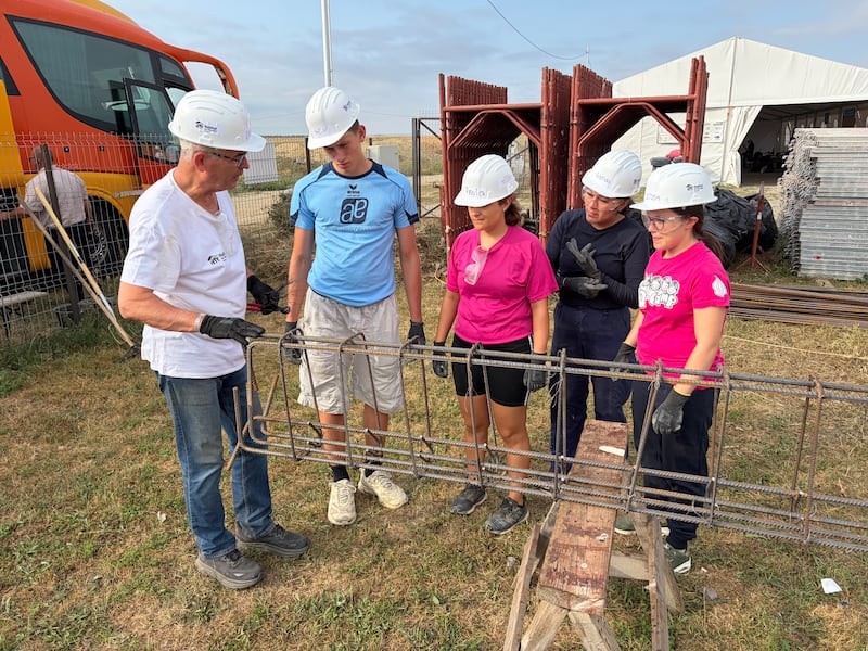 El élder John Dickson, un misionero humanitario de tiempo completo de La Iglesia de Jesucristo de los Santos de los Últimos Días, trabaja con jóvenes adultos preparando acero reforzado durante un proyecto de servicio de Habitat for Humanity Romania en Berceni, Rumania, en agosto de 2026.