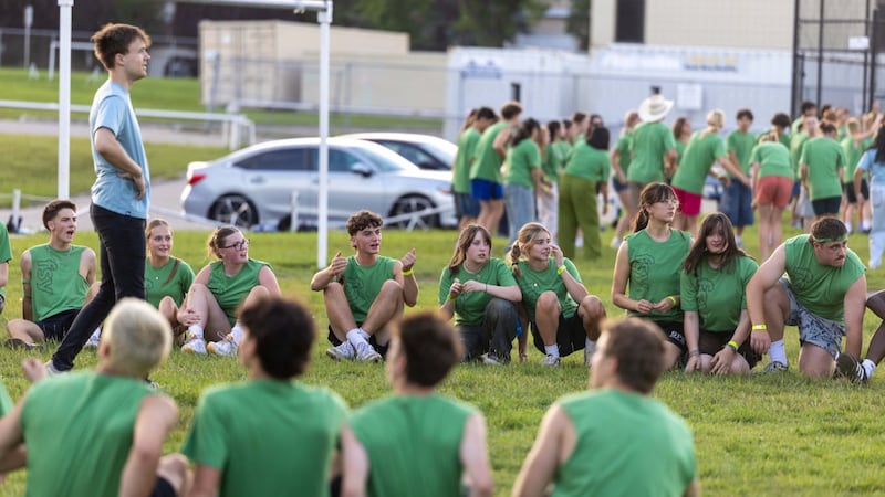 Jóvenes se sientan y se paran en un campo al comienzo de una actividad en FSY en Calgary, Alberta, Canadá, en julio de 2026.