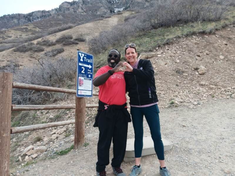 Shiller Joseph, left, and Krissy Miller make a heart with their hands while standing on the Hike the Y Trail, where they first met in September 2023.