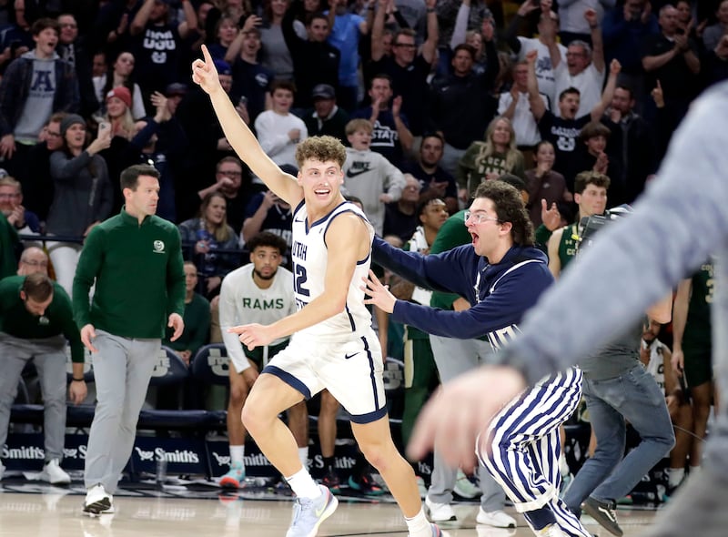 Un aficionado de Utah State corre hacia la cancha para celebrar la victoria de los Aggies sobre el número 13, Colorado State, junto al guardia de primer año Mason Falslev en el Spectrum, en Logan, Utah, el 6 de enero de 2024.