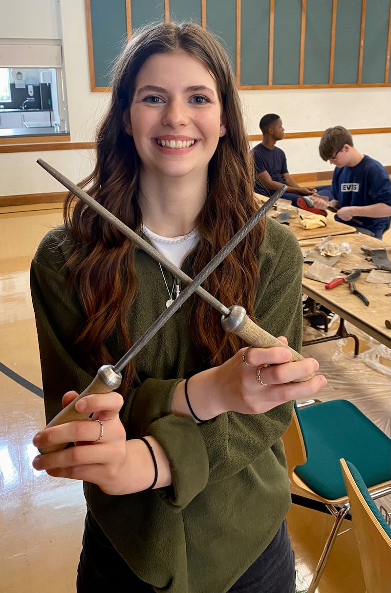 Una mujer joven de la Estaca Northampton Inglaterra muestra herramientas antiguas que están siendo restauradas para donarlas a la organización llamada Tools with a Mission en abril de 2024.