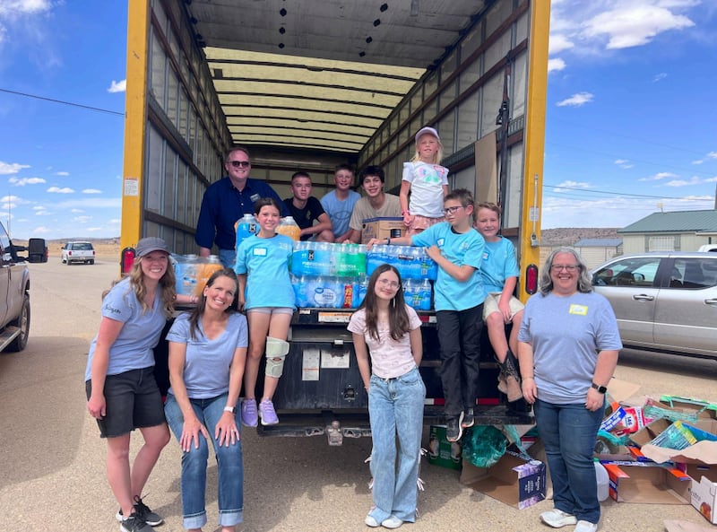 Niños, jóvenes y adultos en Albuquerque, Nuevo México sonríen junto a un camión lleno de agua donada para ayudar a la escasez de agua en la comunidad de To'hajilee el 6 de mayo de 2026.