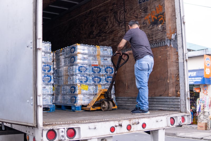 Trabajadores descargan 48,000 botellas de agua purificada para su distribución inmediata a centros educativos en el área metropolitana de San Salvador.
