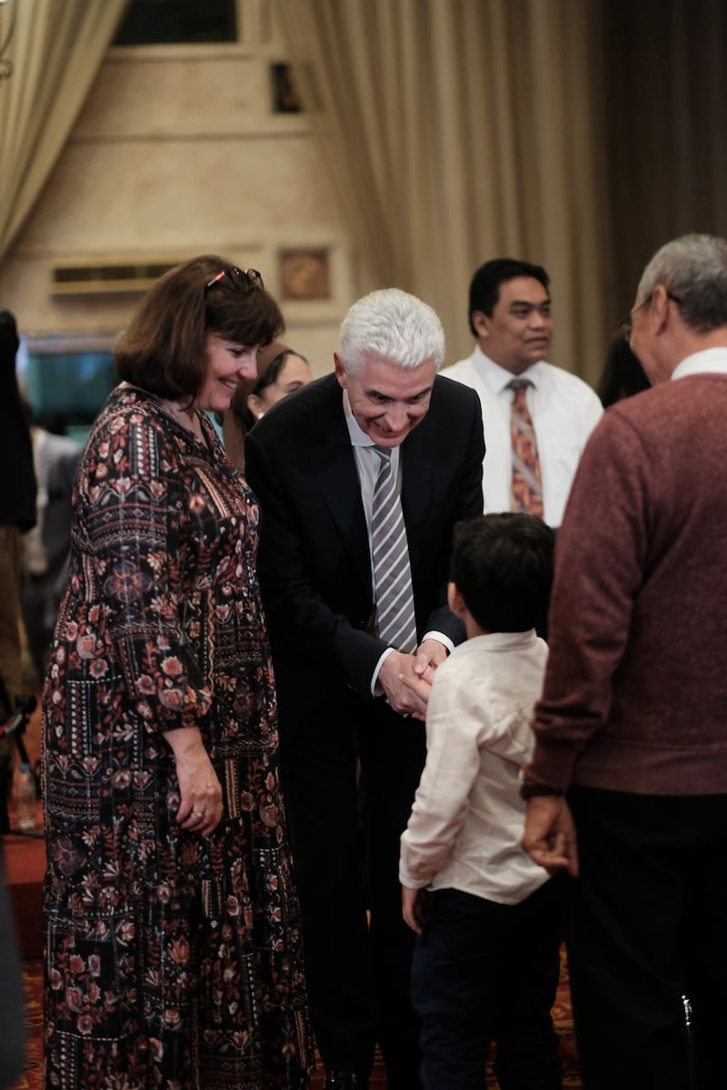 El élder Gérald Caussé, del Cuórum de los Doce Apóstoles, y la hermana Valérie Caussé saludan a un joven miembro antes de la reunión devocional para miembros en Yakarta, Indonesia, el 21 de abril de 2026.