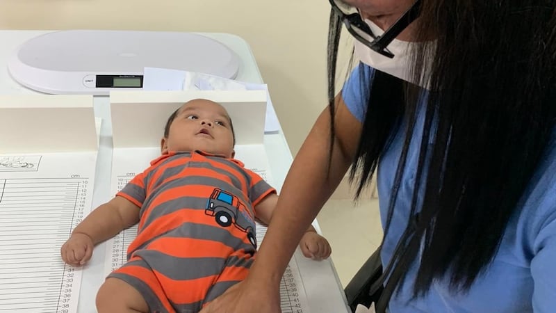Un trabajador de la salud mide la longitud de un bebé durante una evaluación en el Centro de Estaca de Sipocot, Filipinas, el 21 de julio de 2022.