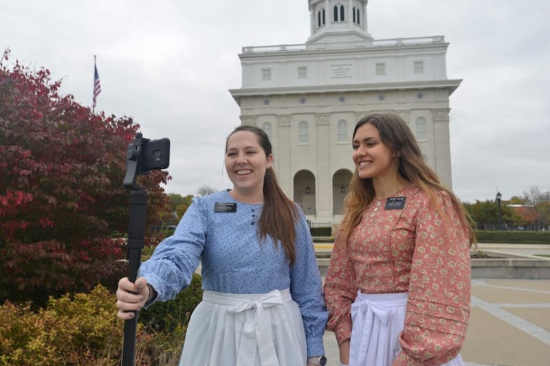 La hermana Karly Robison y la hermana Meg Taylor, misioneras que prestan servicio en los sitios históricos de Nauvoo, dan un recorrido virtual frente al Templo de Nauvoo, Illinois. Debido al COVID-19, los sitios históricos de la Iglesia han estado cerrados desde marzo de 2020.