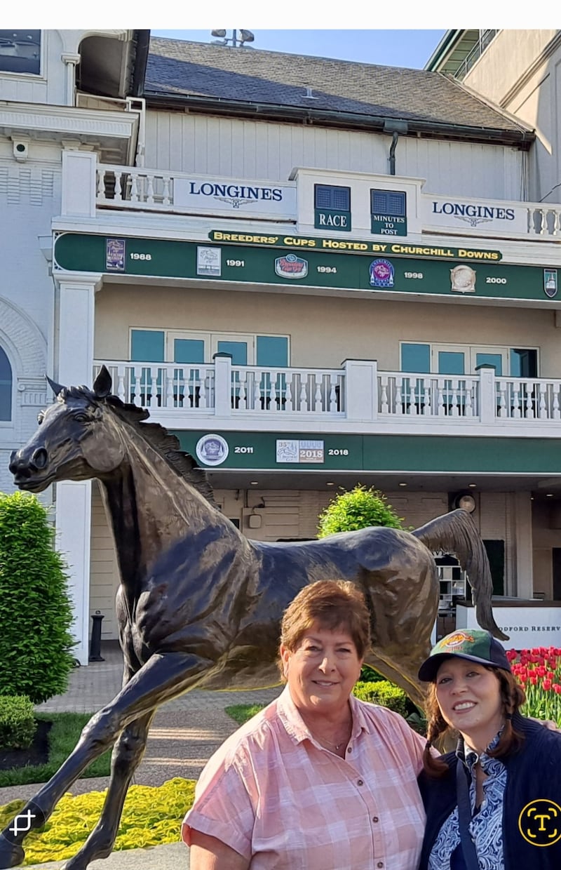 Terry Fiet y Shelly Salyers posan para una foto frente a Churchill Downs en Louisville, Kentucky, donde colaboraron con una organización sin fines de lucro que provee suministros a las familias que trabajan con los caballos.