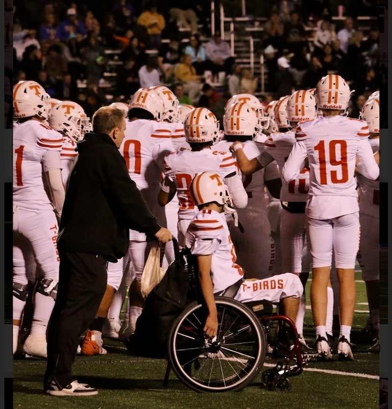 El padre Ken Cooper empuja a su hijo, Matthew Cooper, en su silla de ruedas en la línea de banda durante un partido de fútbol americano de la escuela secundaria Timpview en Provo, Utah, en el otoño de 2024.