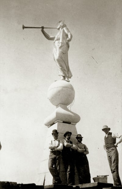 Los trabajadores que estaban terminando el Templo de Salt Lake en 1893 posan para una fotografía en la aguja bajo la estatua del ángel Moroni de Cyrus Dallin.