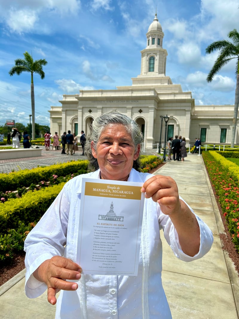 Betty Antonia Castro Torres sostiene una tarjeta con las palabras del himno "El Espíritu de Dios Como un Fuego Ardiente" fuera del Templo de Managua Nicaragua después de la dedicación en Managua, Nicaragua, el domingo 18 de octubre de 2026.