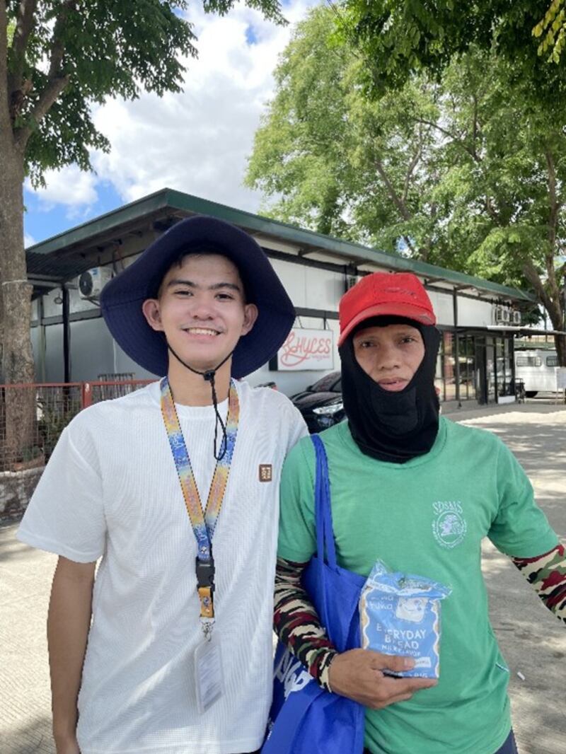 Rodolfo Gallinero III, a la izquierda, posa para una foto con la persona que recibió un paquete de cuidados ensamblado por estudiantes jóvenes en Santo Tomás, Filipinas, el 1 de mayo de 2026.