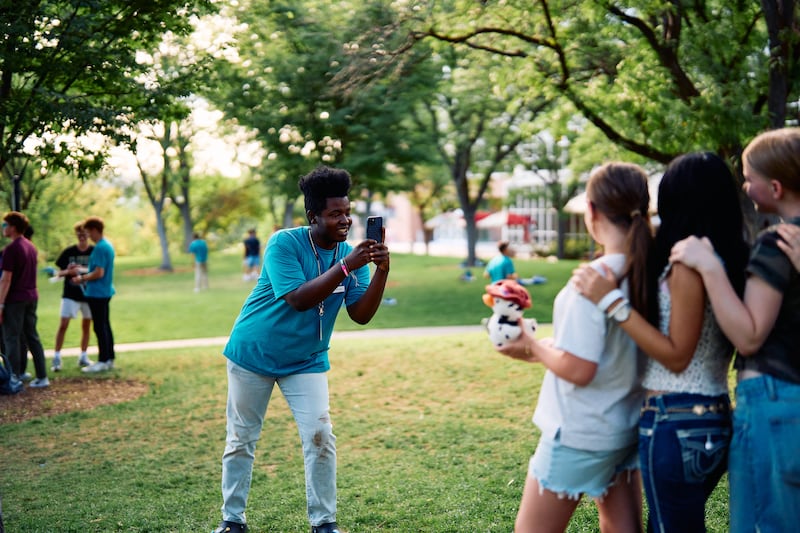 Un consejero de FSY toma una foto de tres jóvenes en una conferencia Para la Fortaleza de la Juventud en Salt Lake City en 2025.