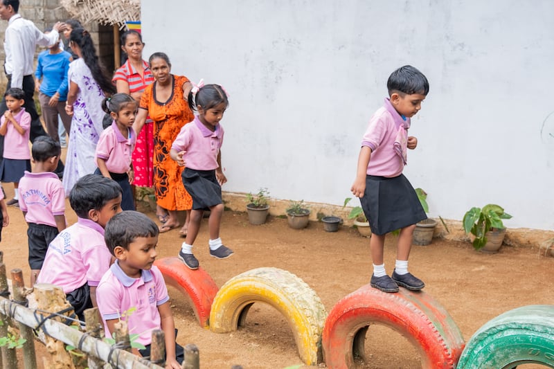 Niños pequeños juegan afuera de una escuela en Sri Lanka.