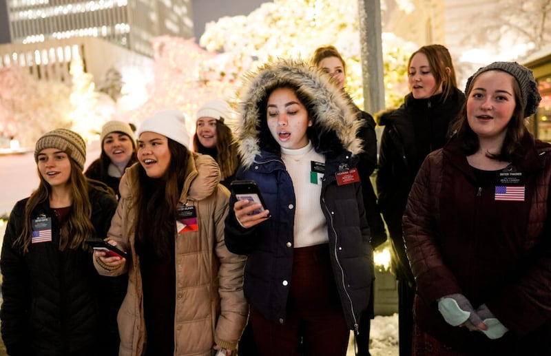Misioneras de La Iglesia de Jesucristo de los Santos de los Últimos Días entonan cantos Navideños mientras la gente disfruta la primera noche del encendido anual de las luces Navideñas en la Manzana del Templo, en Salt Lake City, Utah, el viernes 29 de noviembre de 2019.
