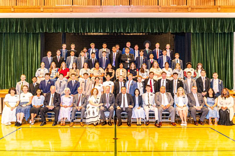 Los misioneros de la Misión California Oakland/San Francisco posan para una foto grupal grande junto al escenario de una capilla durante una conferencia de zona en 2025.