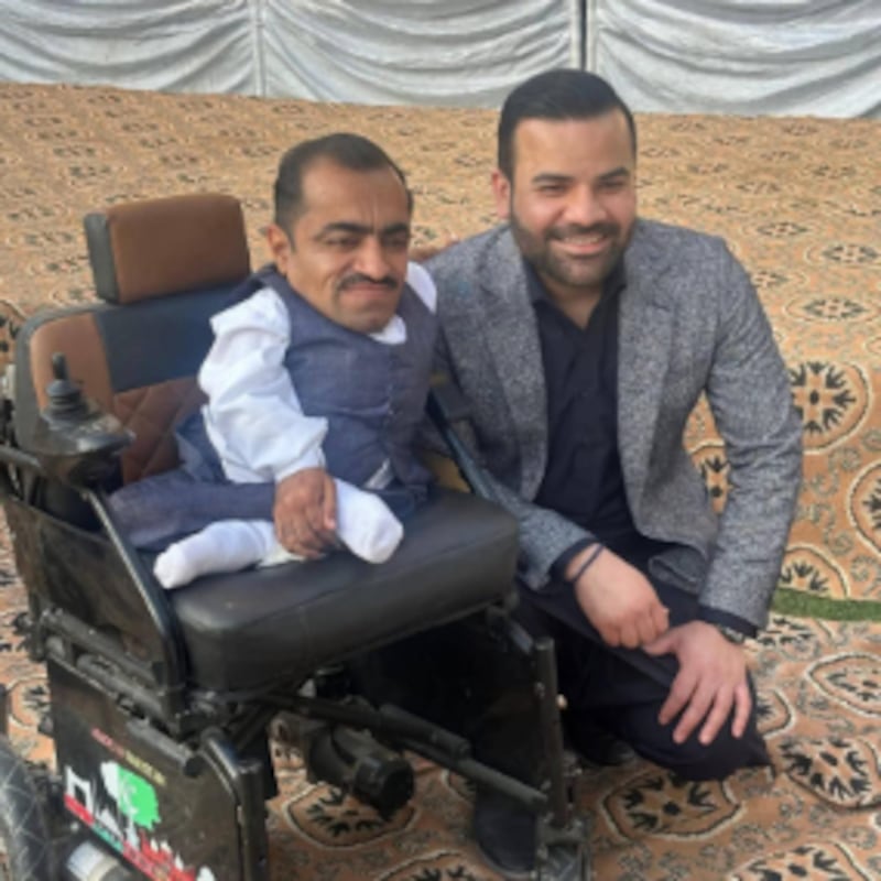 El Ministro de Estado de Pakistán Barrister Aqueel Malik posa con un beneficiario de silla de ruedas durante un evento de entrega el 13 de febrero de 2026 en la ciudad de Taxila, Pakistán.