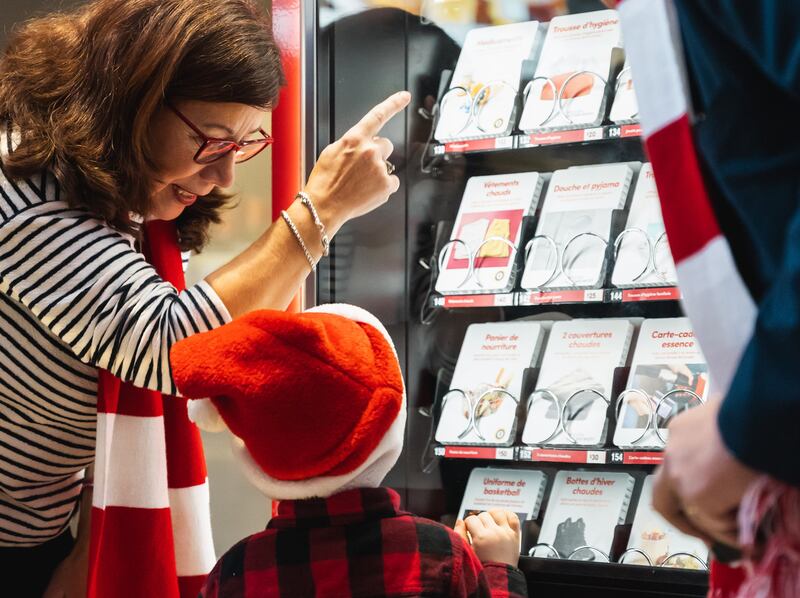 Una familia observa las tarjetas de donación en una máquina de donaciones de Ilumina el Mundo en Montreal, Quebec, Canadá, en diciembre de 2025.