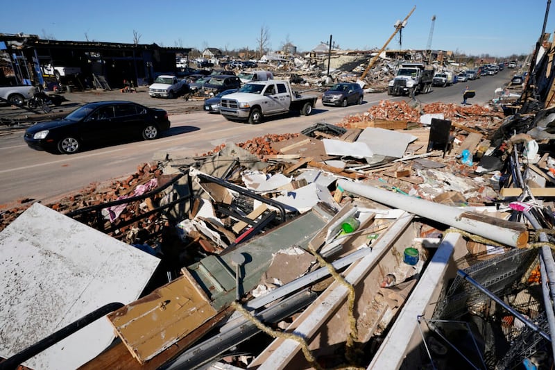 El tráfico avanza lentamente en las calles llenas de escombros el domingo, 12 de diciembre de 2021 en Mayfield, Kentucky. Los tornados y el clima severo causaron daños catastróficos en varios estados el viernes, matando a varias personas durante la noche.