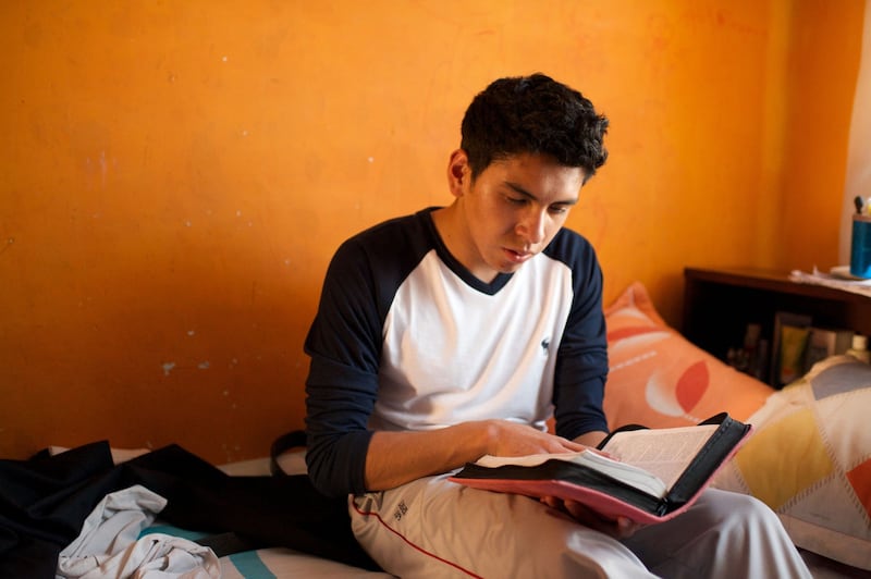 Un joven miembro de La Iglesia de Jesucristo de los Santos de los Últimos Días lee las escrituras en su dormitorio en Bolivia.