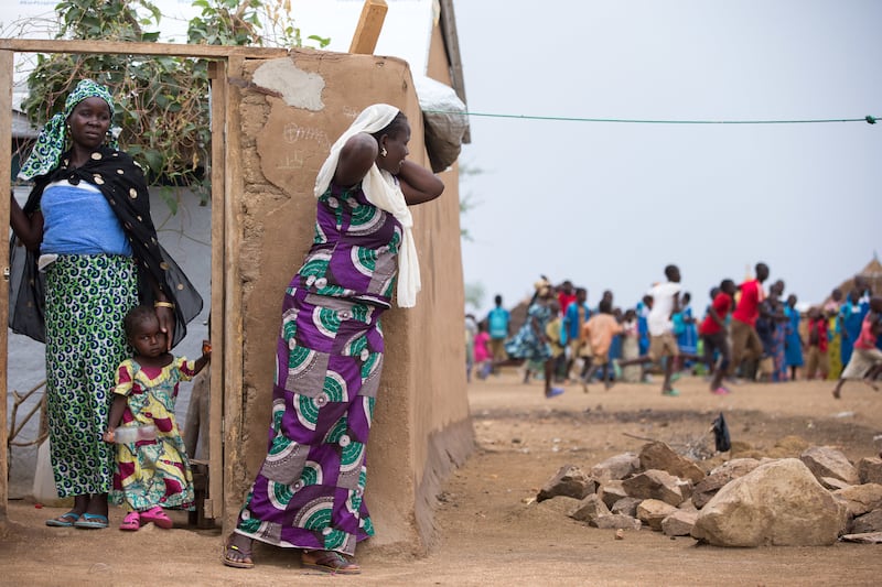 Refugiados de pie fuera de los refugios se reúnen cuando un visitante llega al campamento de refugiados de Minawao, en el norte de Camerún, el lunes 18 de abril de 2016.