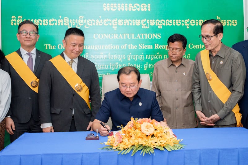 Chheang Ra, ministro de Salud de Camboya, al centro, junto con el élder Benjamin M.Z. Tai, Setenta Autoridad General y presidente del Área Asia, al centro a la izquierda, firma un libro conmemorativo en la ceremonia que celebra el nuevo centro cardiaco.