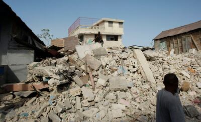 Un transeúnte se cubre la boca del polvo mientras camina en Puerto Príncipe, Haití, el 19 de enero de 2010 — una semana después de que un terremoto de magnitud 7,0 azotara la región.