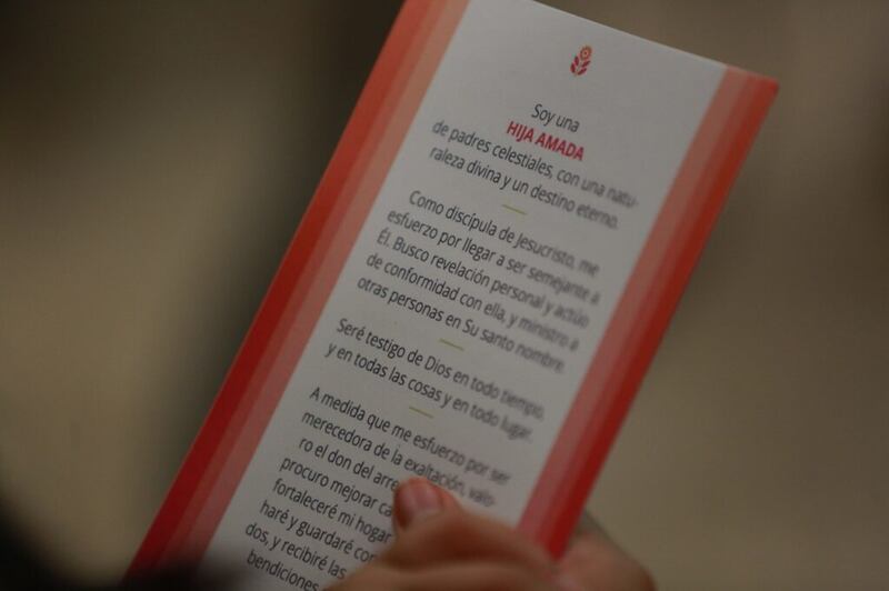 Una mujer joven sostiene el lema de las Mujeres Jóvenes en la mano durante un devocional el 5 de junio de 2022.