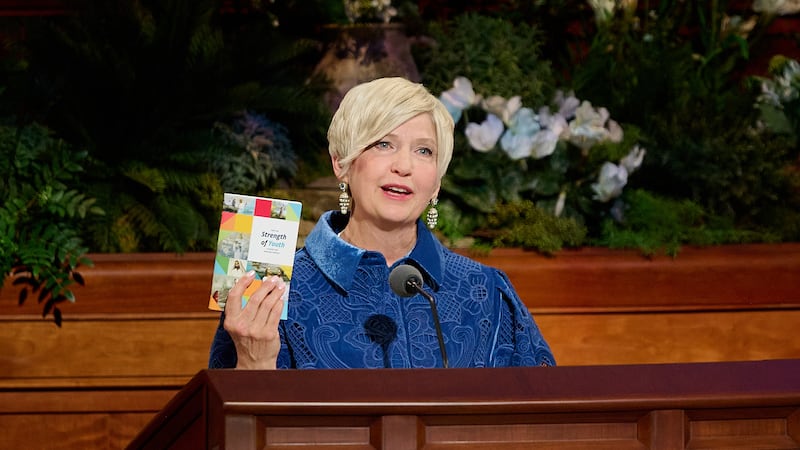 La Presidenta General de las Mujeres Jóvenes, Emily Belle Freeman, sostiene un ejemplar de "Para la fortaleza de la juventud" mientras habla durante la sesión del domingo por la mañana de la 196ª Conferencia General Anual de La Iglesia de Jesucristo de los Santos de los Últimos Días, en el Centro de Conferencias en Salt Lake City, el 5 de abril de 2026.