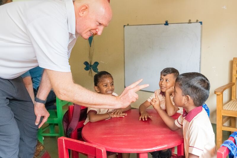 El élder Kelly R. Johnson interactúa con niños en una escuela en Sri Lanka.