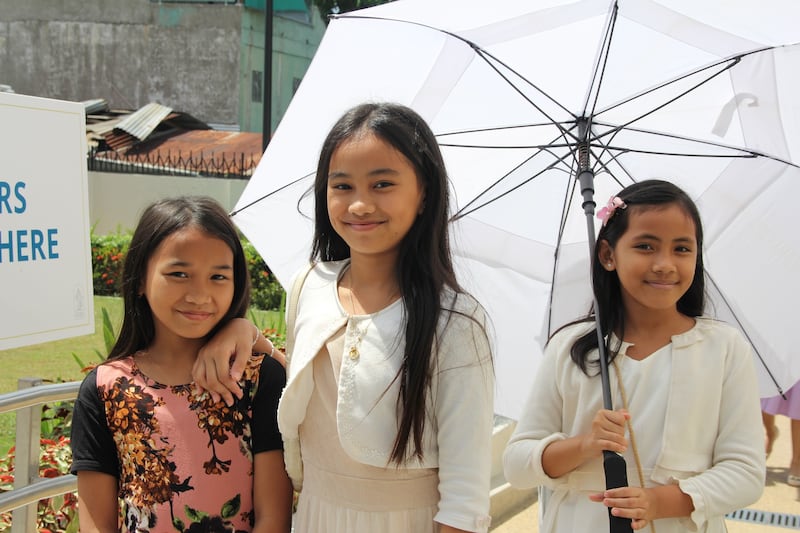 Tres niñas sonríen para una foto frente al Templo de Davao, Filipinas, el último día de la jornada de casa abierta al público, el 10 de abril de 2026.