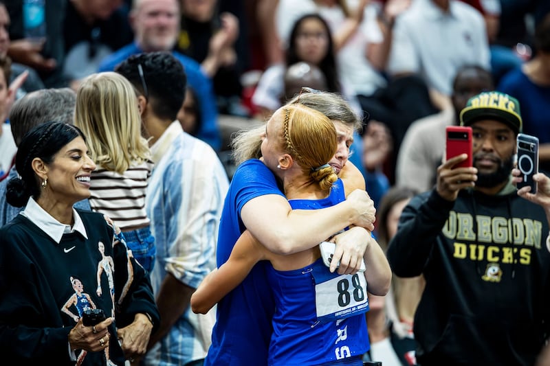 Jane Hedengren, de BYU, recibe un abrazo después de ganar un título nacional en la carrera de 5,000 metros.