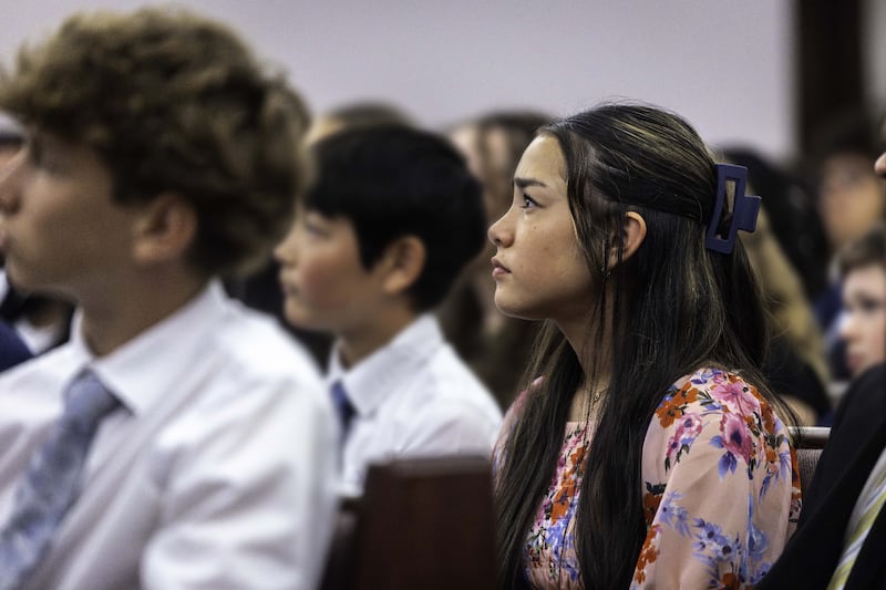 Una joven y otros jóvenes en Toronto, Canadá, escuchan al presidente D. Todd Christofferson, segundo consejero de la Primera Presidencia, en un devocional el sábado 13 de junio de 2026.
