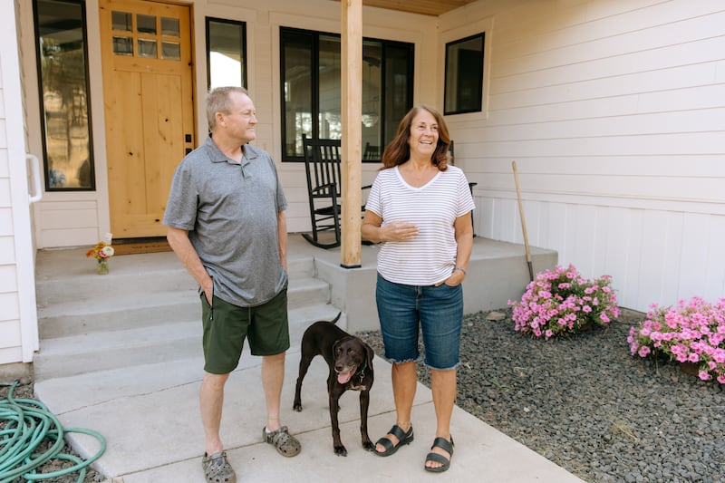 De pie afuera con su perro Mia, Todd y Debbie Rogers cuentan la historia de cómo su hogar sobrevivió los incendios forestales de Spokane en Spokane, Washington, el sábado 22 de agosto de 2026.
