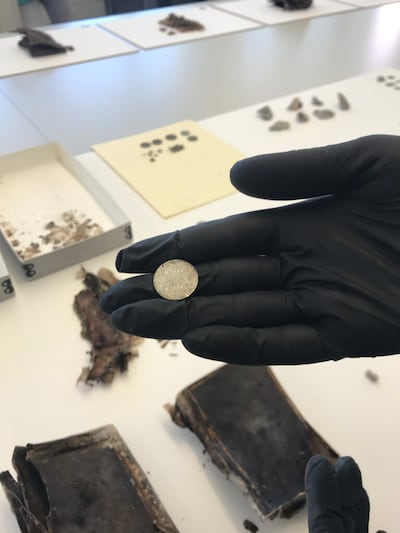 Emily Utt, curadora de sitios históricos de la Iglesia, muestra una moneda que se encontró en la piedra de coronamiento del Templo de Salt Lake grabada con el nombre de Alice Hillam, prima hermana del abuelo de la presidenta general de las Mujeres Jóvenes, Bonnie H. Cordon.