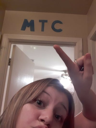 La hermana Hannah Hargrave señala el letrero improvisado del CCM sobre la puerta de su casa en San Tan Valley, Arizona, donde está recibiendo capacitación en línea por medio de videoconferencias en calidad de nueva misionera, en marzo de 2020. Debido a que las operaciones de capacitación estándar se suspendieron en los 10 centros de capacitación misional de la Iglesia a raíz de la pandemia del COVID-19, los nuevos misioneros ahora reciben capacitación en su hogar.
